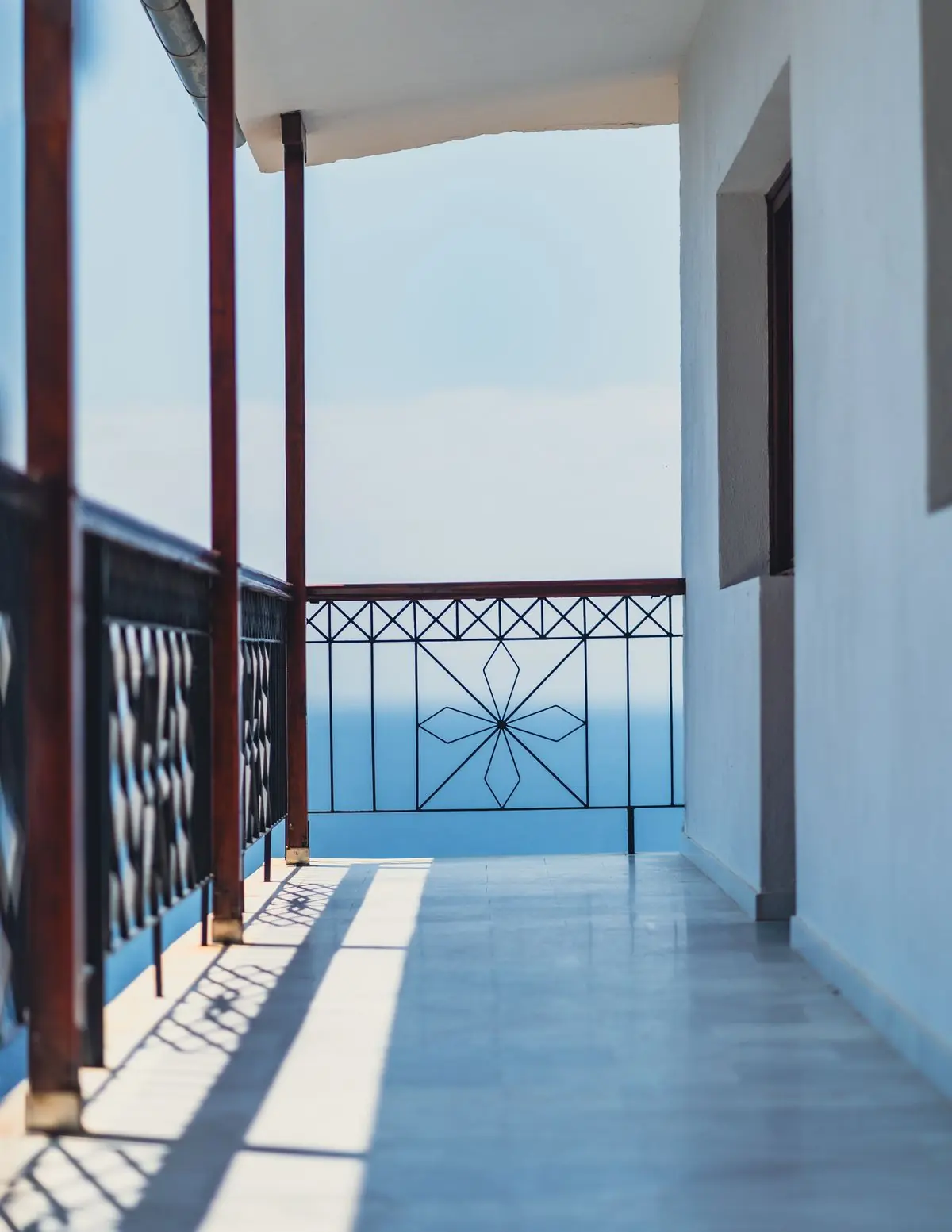 Μακρύ μπαλκόνι με γαλάζια κάγκελα, η θάλασσα από πίσω