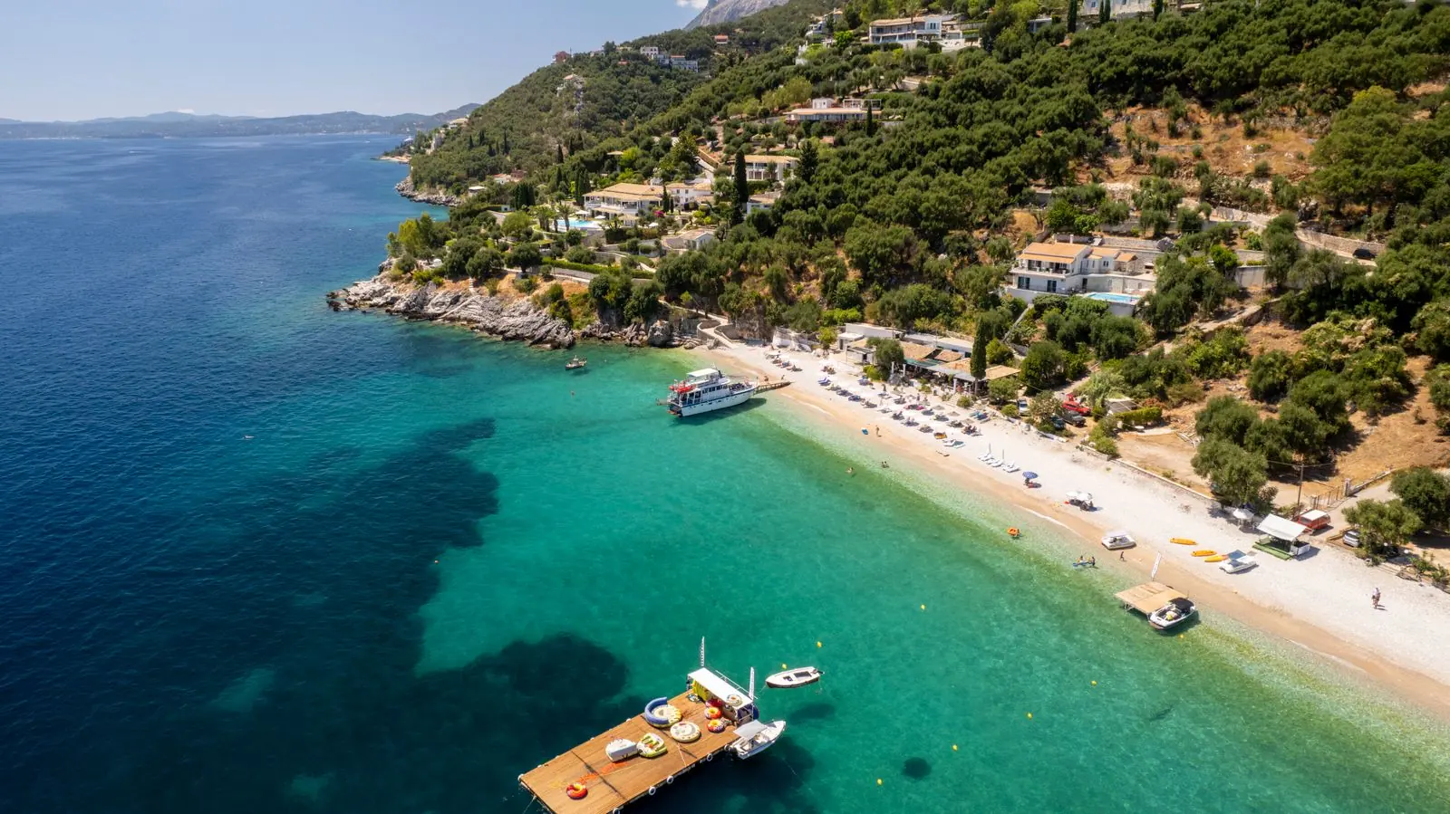 Ο κόλπος από ψηλά, με την ξύλινη εξέδρα, τις βάρκες και τους πράσινους λόφους