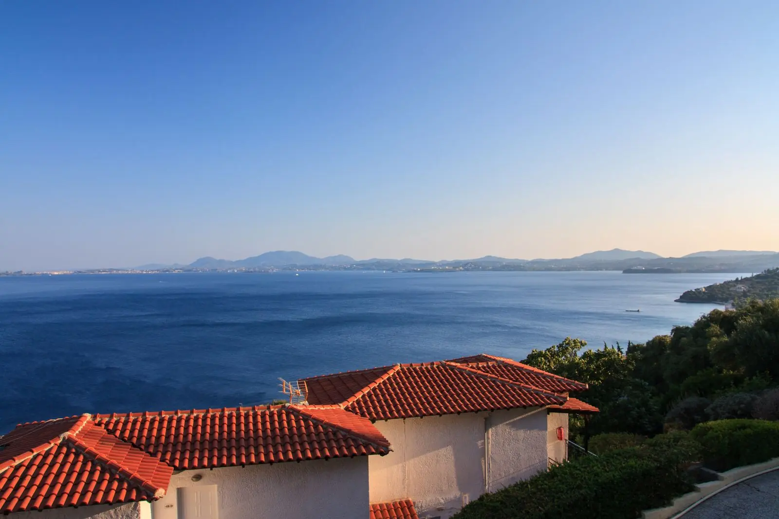 Λευκά σπίτια με κεραμιδένιες στέγες πάνω από το Ιόνιο