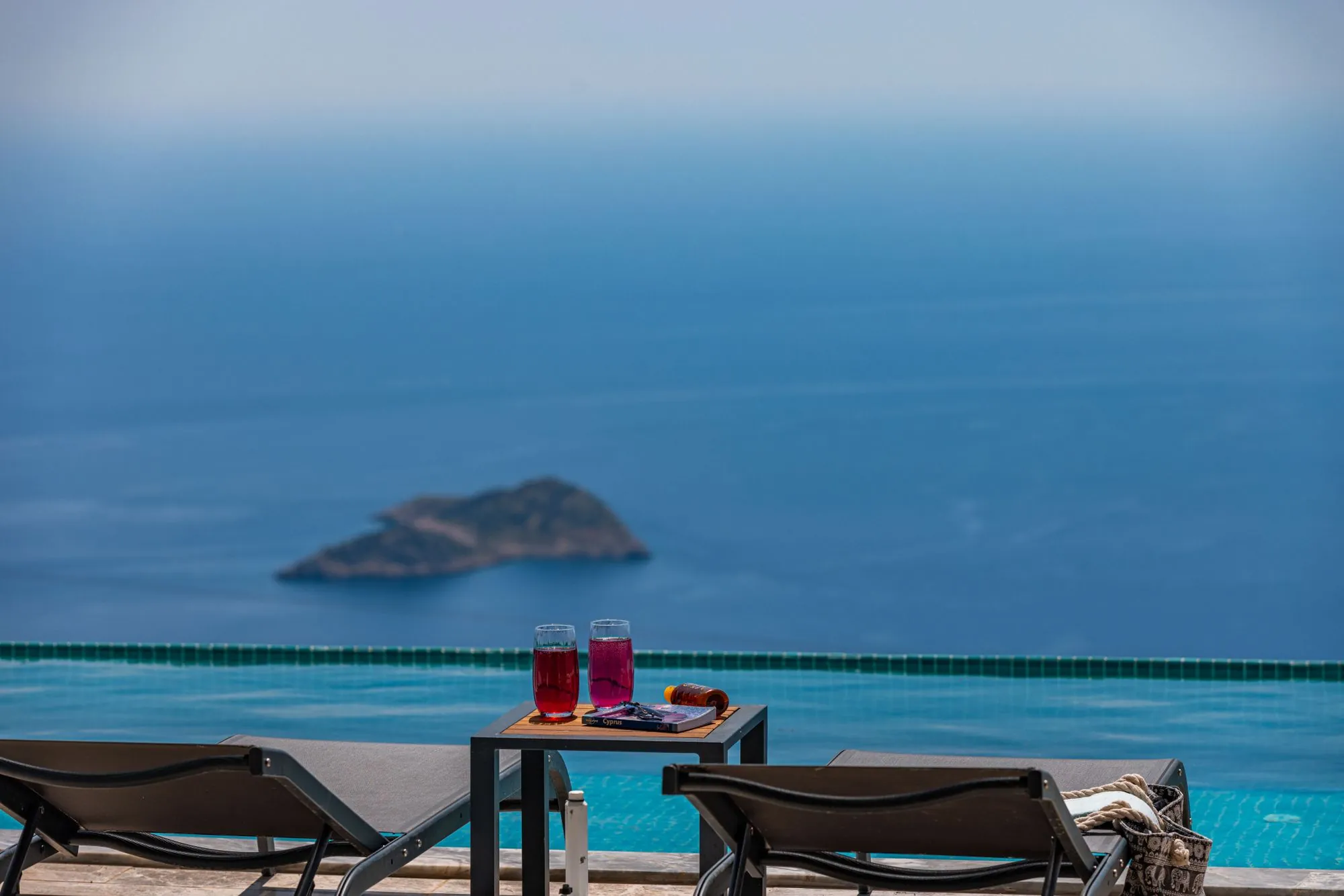 Ξαπλώστρες στην πισίνα, με ένα νησάκι στη θάλασσα από κάτω